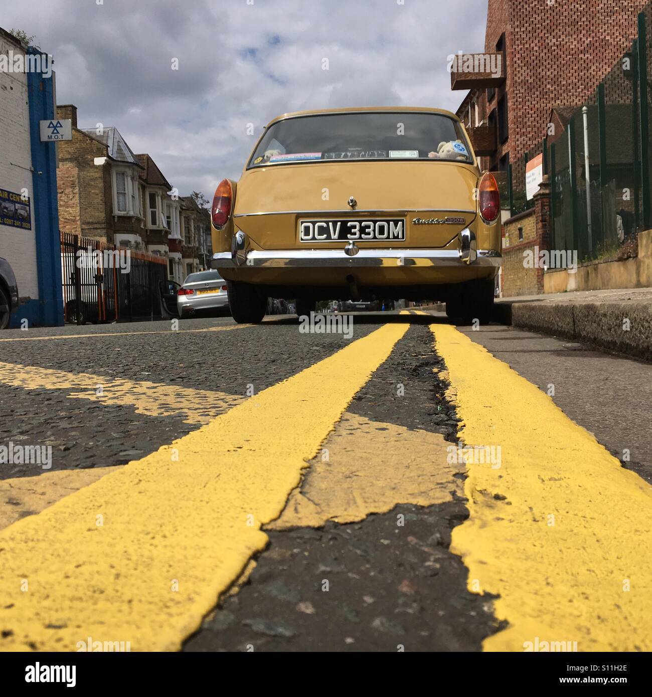 Yellow parking lines and a retro style car photographed from low angle - Smartphone Captured Stock Image