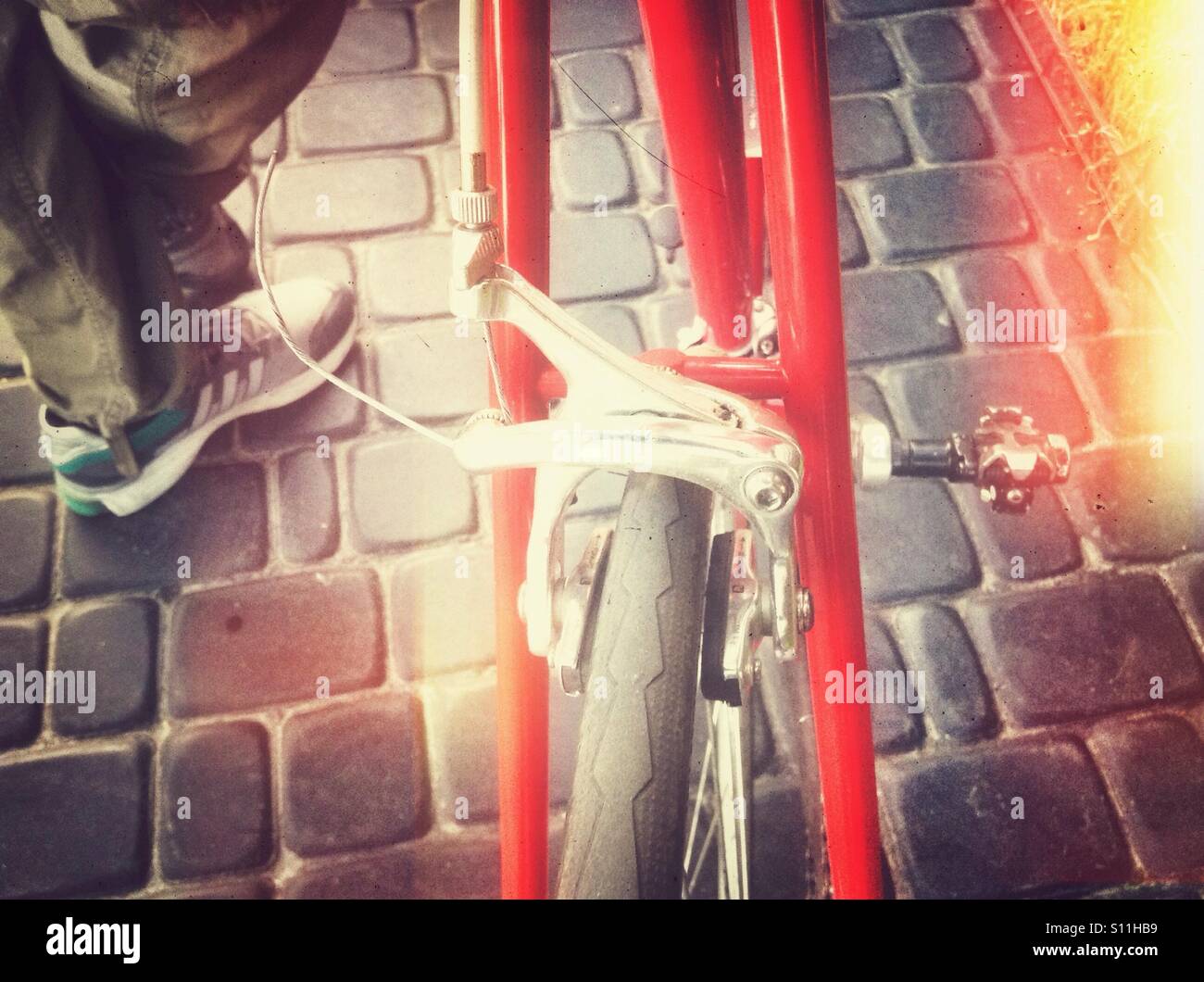 Legs and bicycle details on a paving stone road - Smartphone Captured Stock Image