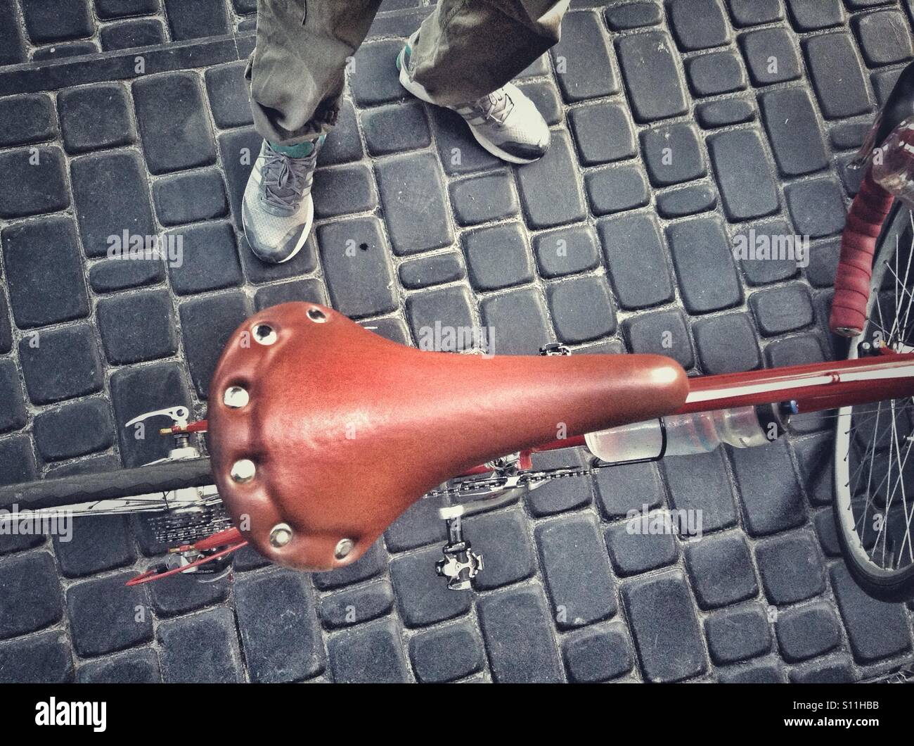 Bicycle seat from above with legs on paving stone road - Smartphone Captured Stock Image