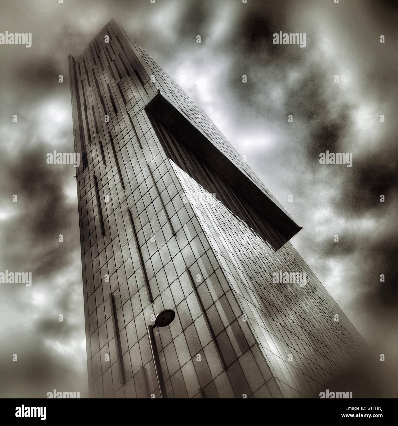 Low-angle view of Beetham Tower under dramatic storm clouds, a modern skyscraper dominating the Manchester skyline. - Smartphone Captured Stock Image