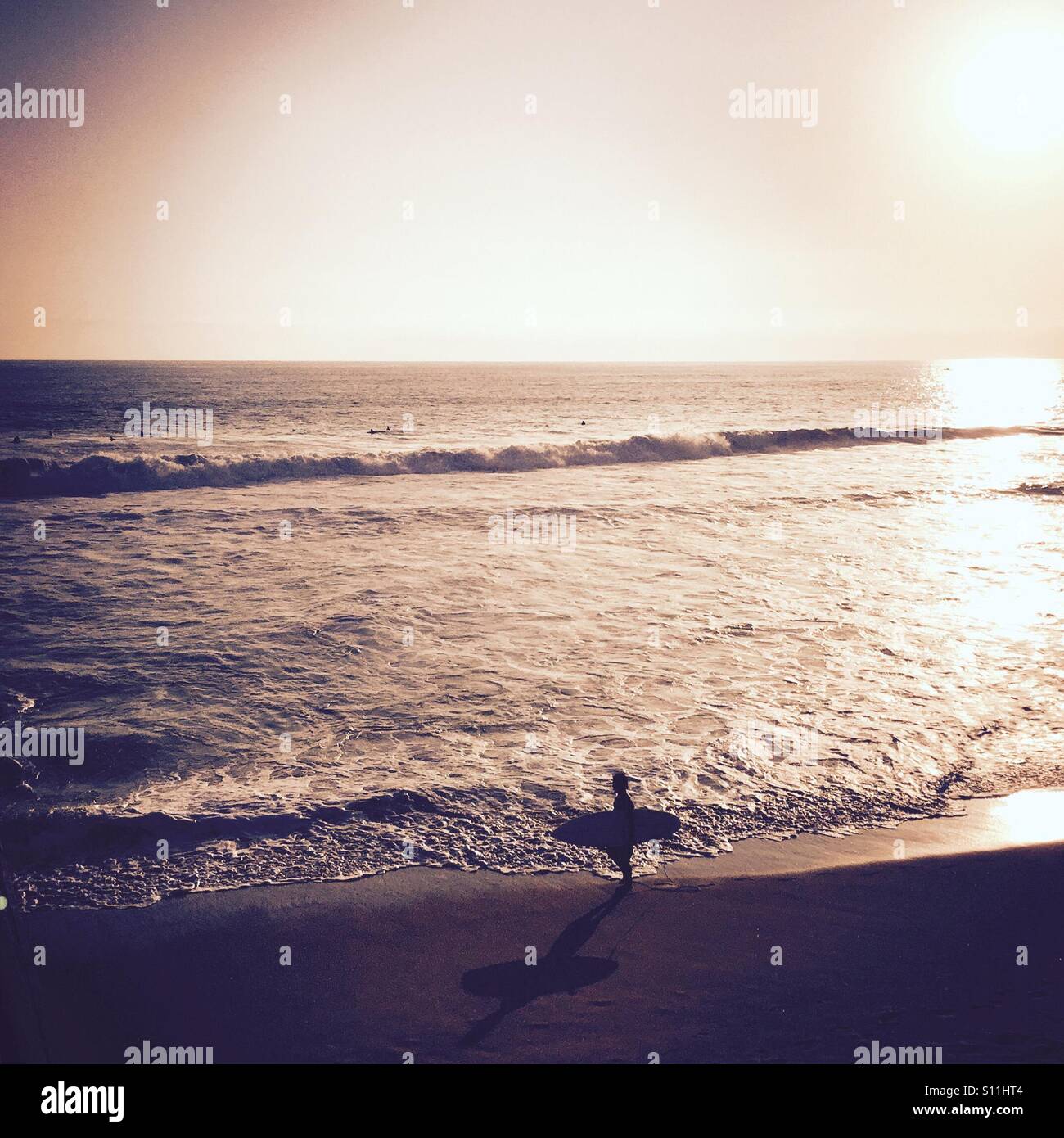 A Surfer walking down the beach checking out the waves. Manhattan Beach, California, USA. Stock Photo