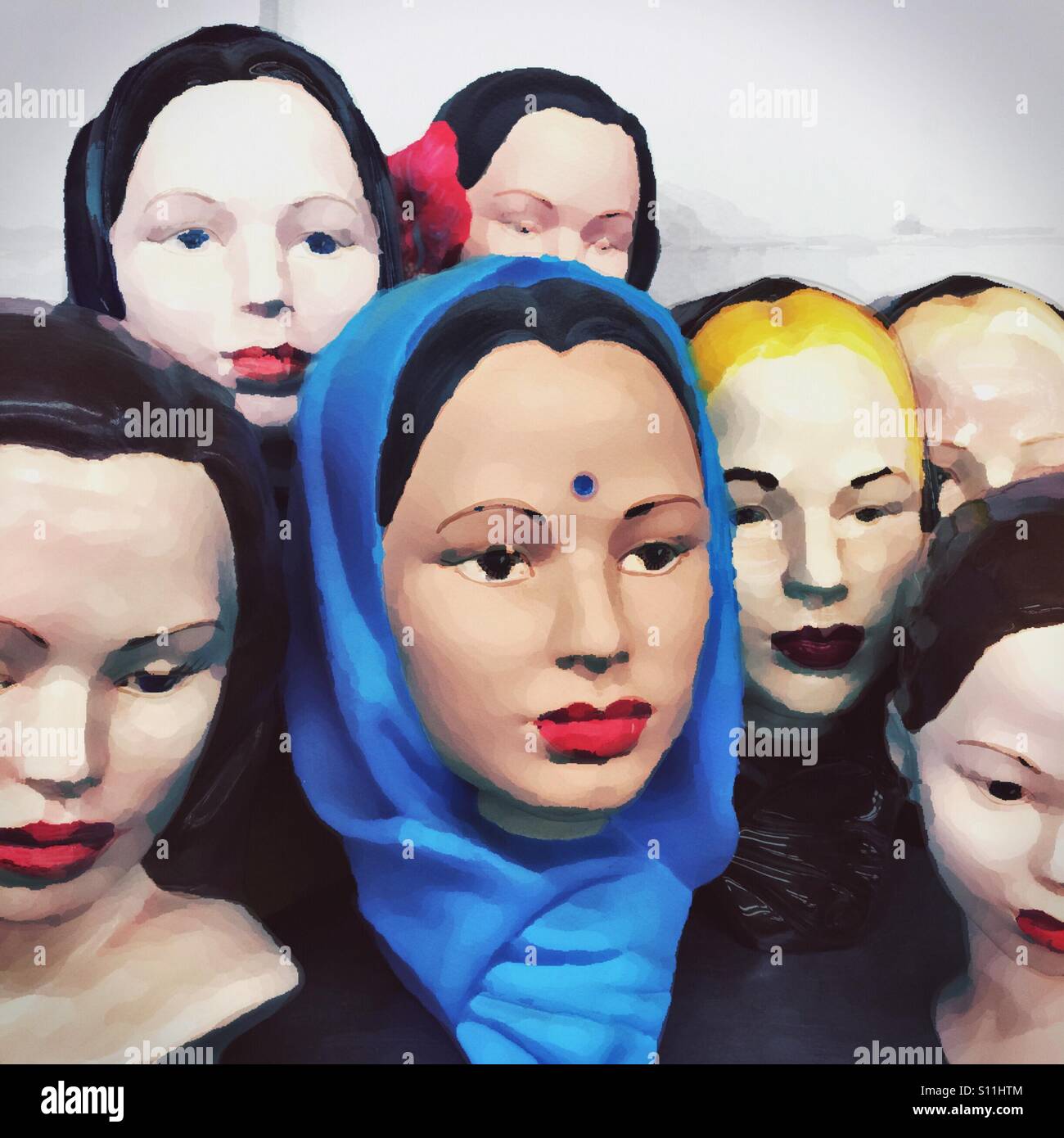 A collection of statues of women's heads arranged in a group with a painting effect.  The woman in the center has a bindi on her forehead and is wearing a veil. Stock Photo