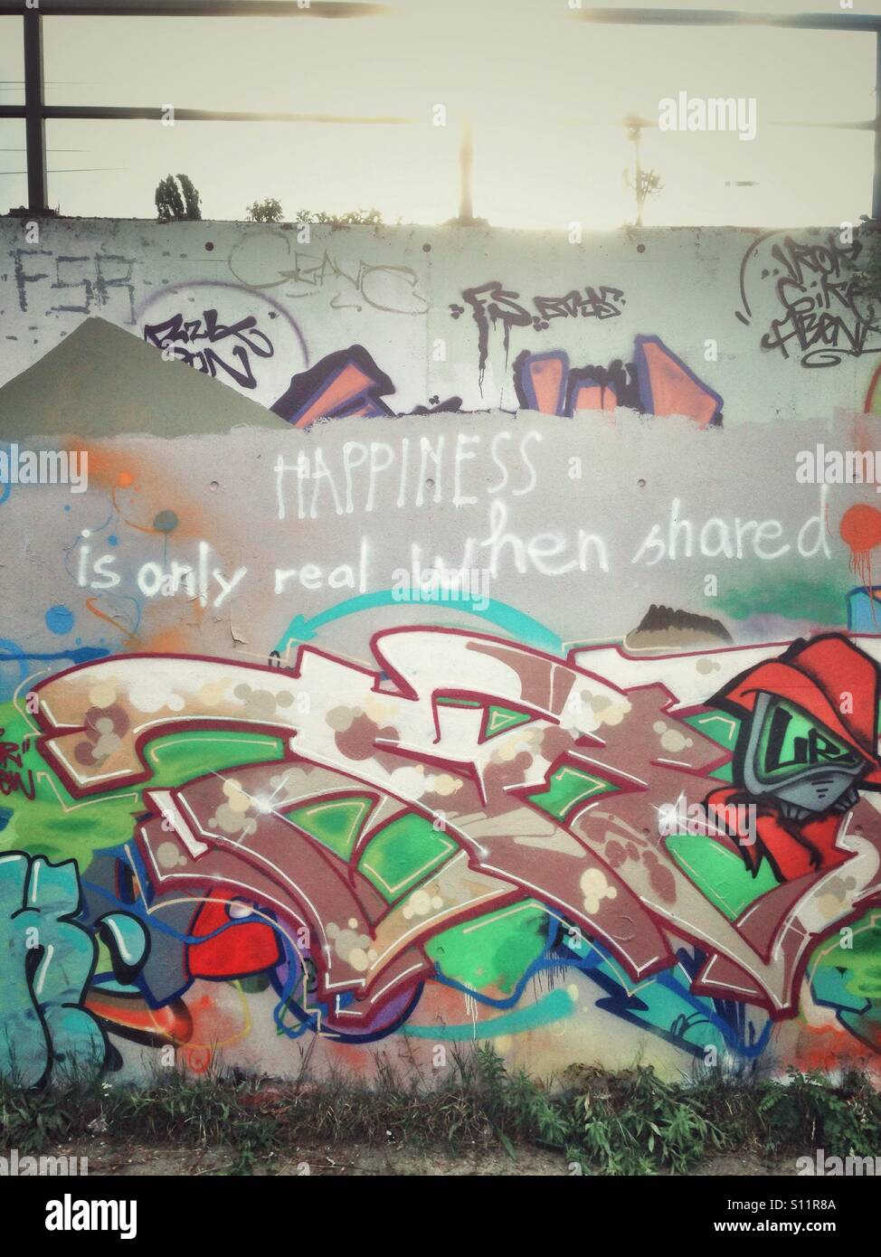 Happiness is only real when shared graffiti on a public graffiti wall in the Berlin Park am Gleisdreieck, Germany Stock Photo