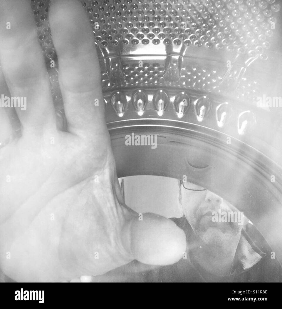 Man emptying a laundry machine. Shot from inside - Smartphone Captured Stock Image