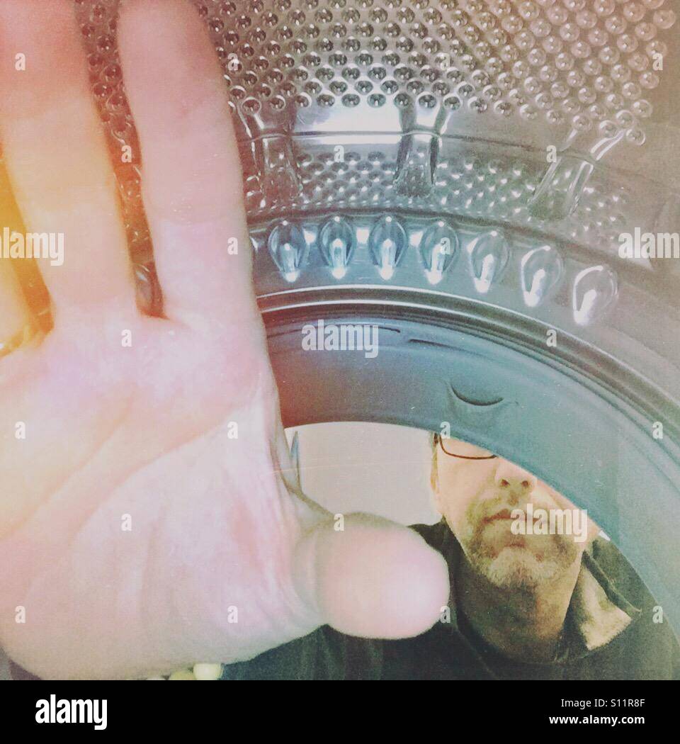 Man emptying a laundry machine. Shot from inside. - Smartphone Captured Stock Image