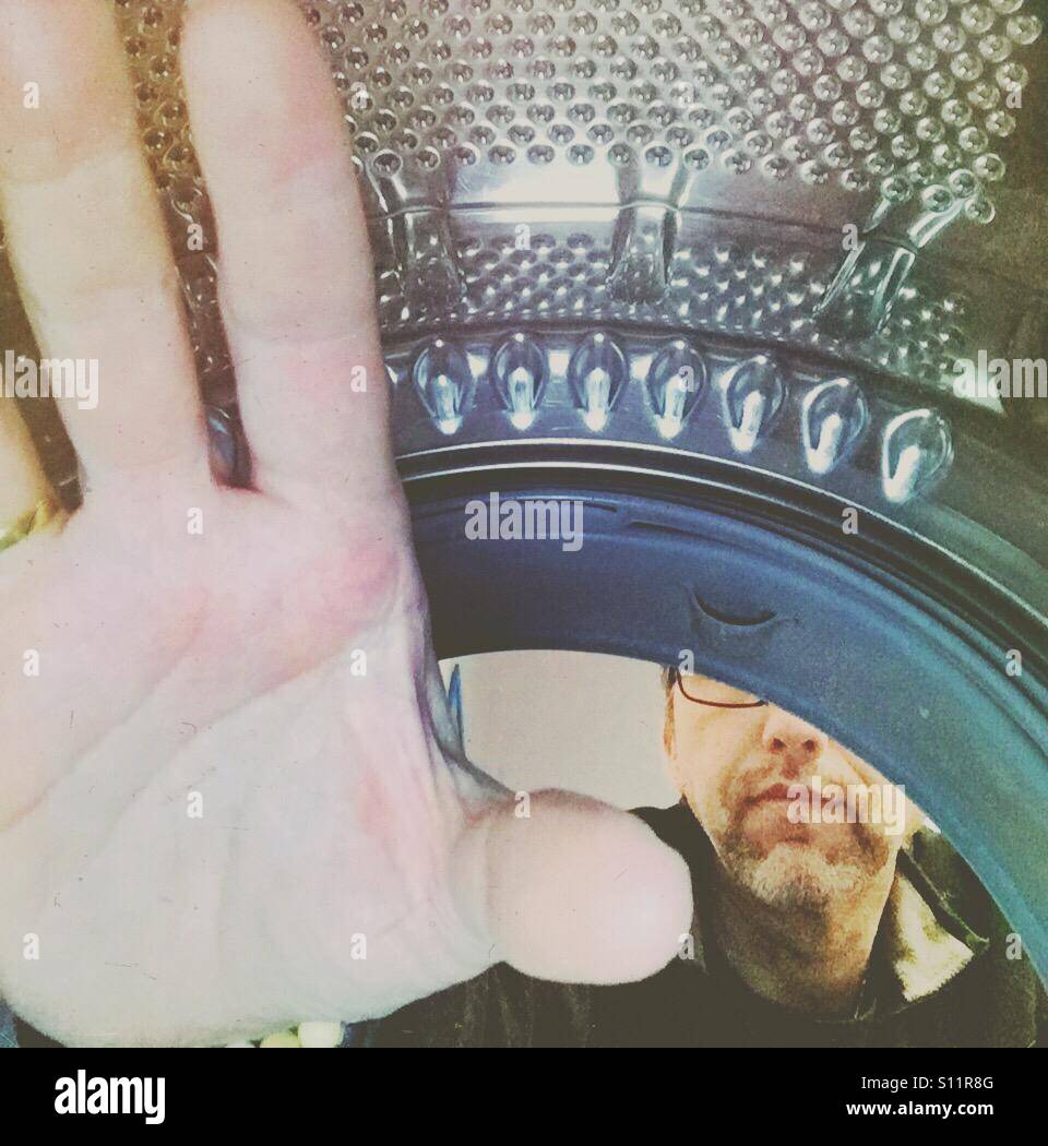 Man emptying a laundry machine. Shot from inside. - Smartphone Captured Stock Image