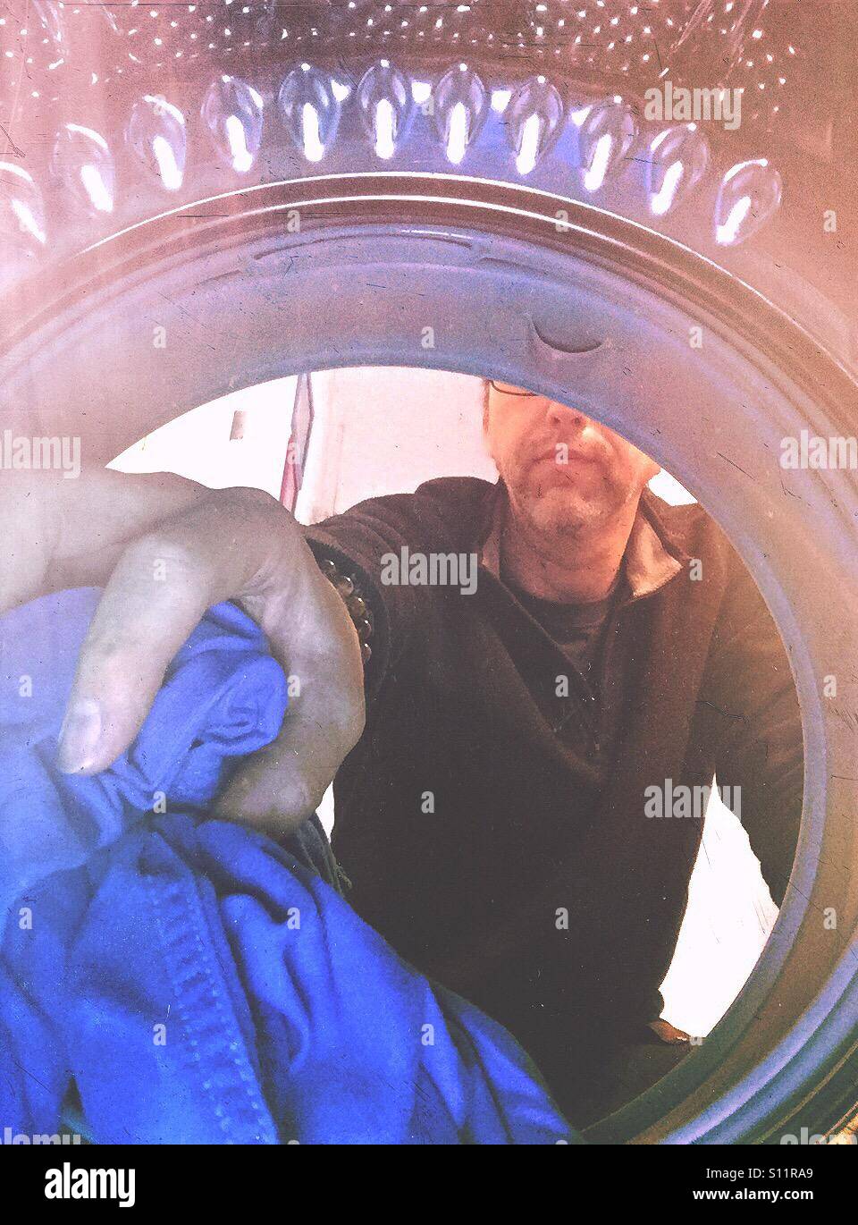Man filling up or emptying a laundry machine. Shot from the inside - Smartphone Captured Stock Image