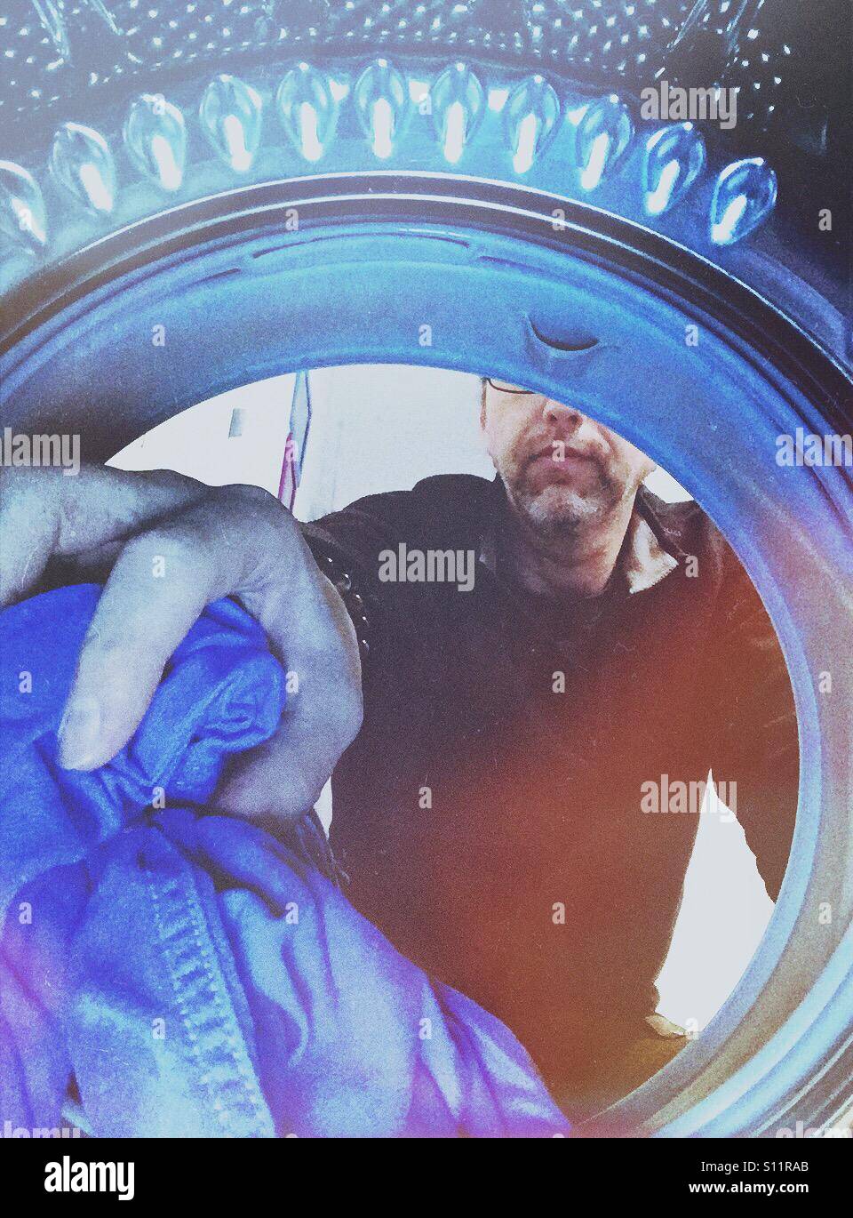 Man emptying or filling up a laundry machine. Shot from the inside - Smartphone Captured Stock Image