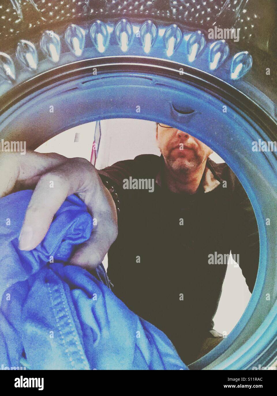 Man emptying or filling up a laundry machine. Shot from the inside. - Smartphone Captured Stock Image