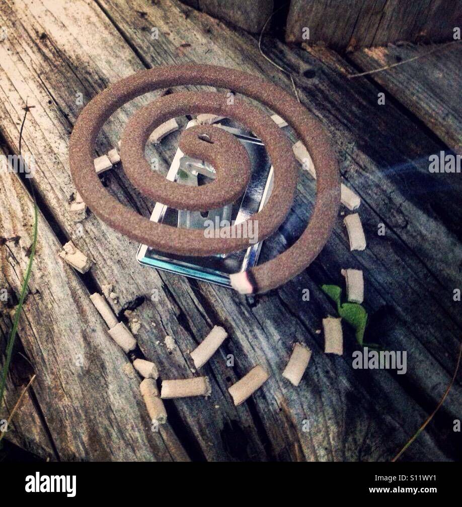 Old fashioned mosquito coil burning and leaving ash below Stock Photo