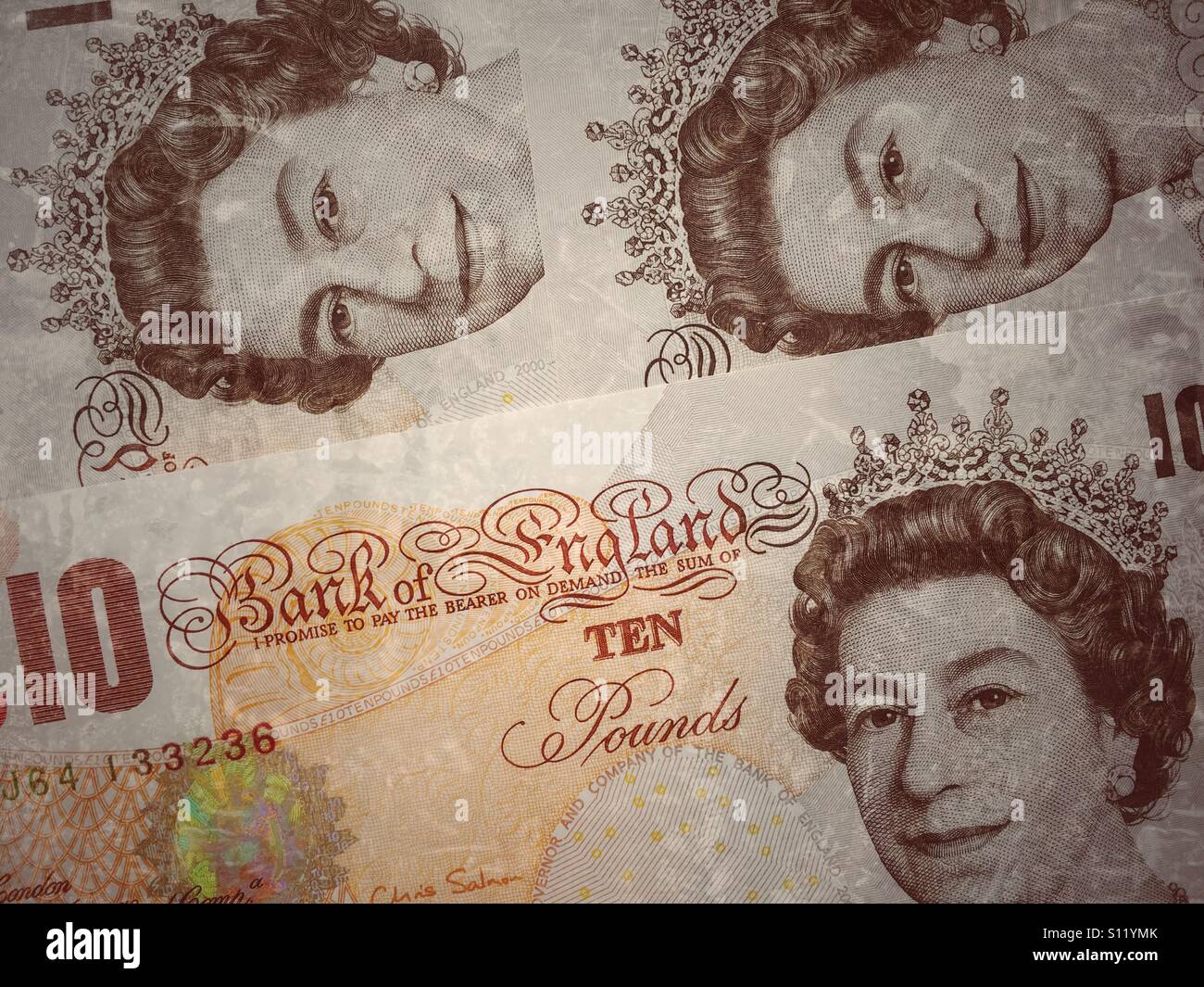 Three Bank of England Ten Pound Notes arranged in a way so that Queen Elizabeth II's portrait is clearly visible. Photograph © COLIN HOSKINS. Stock Photo