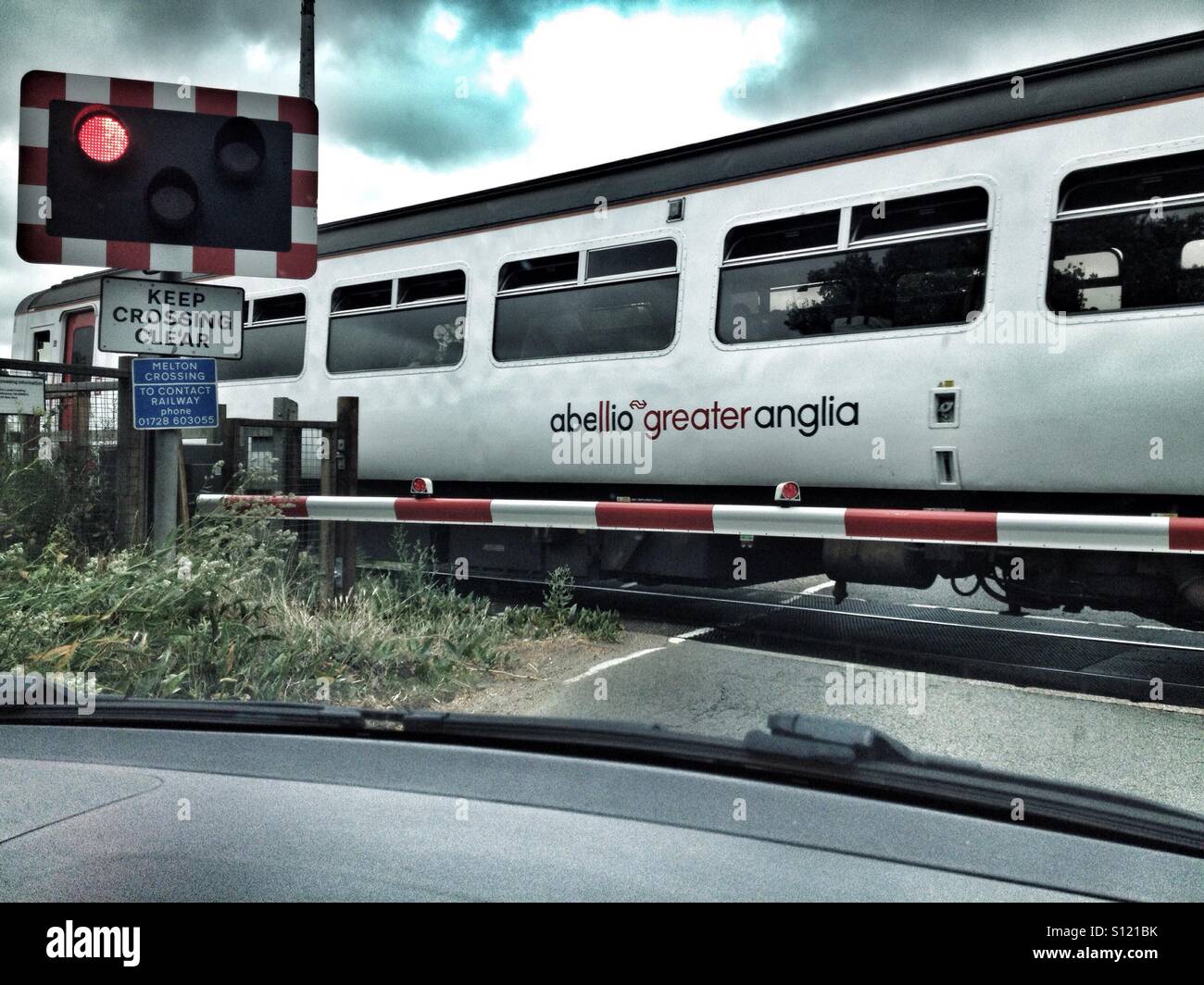 Abellio Greater Anglian passenger train from Ipswich to Lowestoft passing over a level crossing at Melton, Suffolk, UK. - Smartphone Captured Stock Image