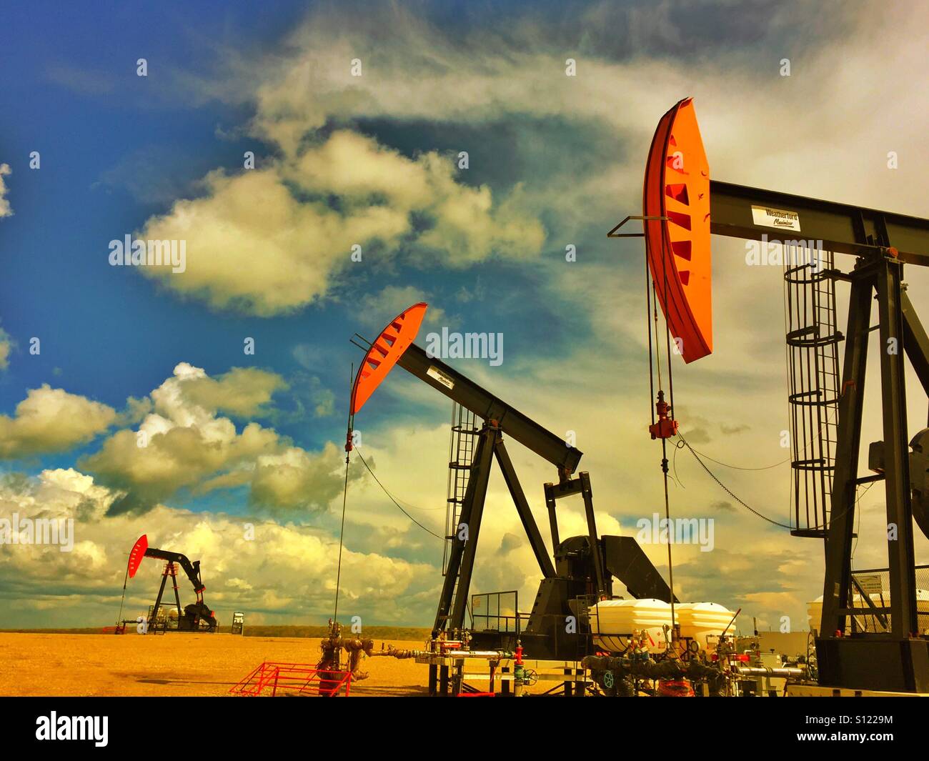 Three Red and black oil well pump jacks - Smartphone Captured Stock Image