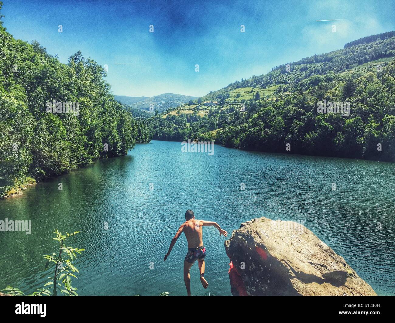 Man jumping in lake Stock Photo
