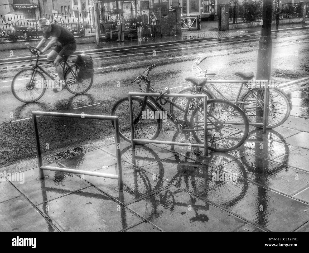 Cyclist on the road behind bike stand reflections in the rain the rain