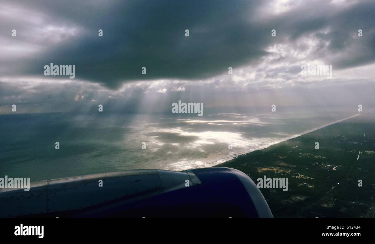 The view from the plane; sun rays from the clouds into the ocean ...