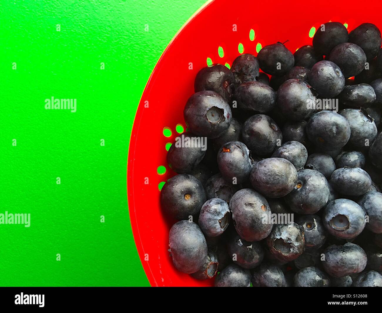Blueberries in red colander on green - Smartphone Captured Stock Image