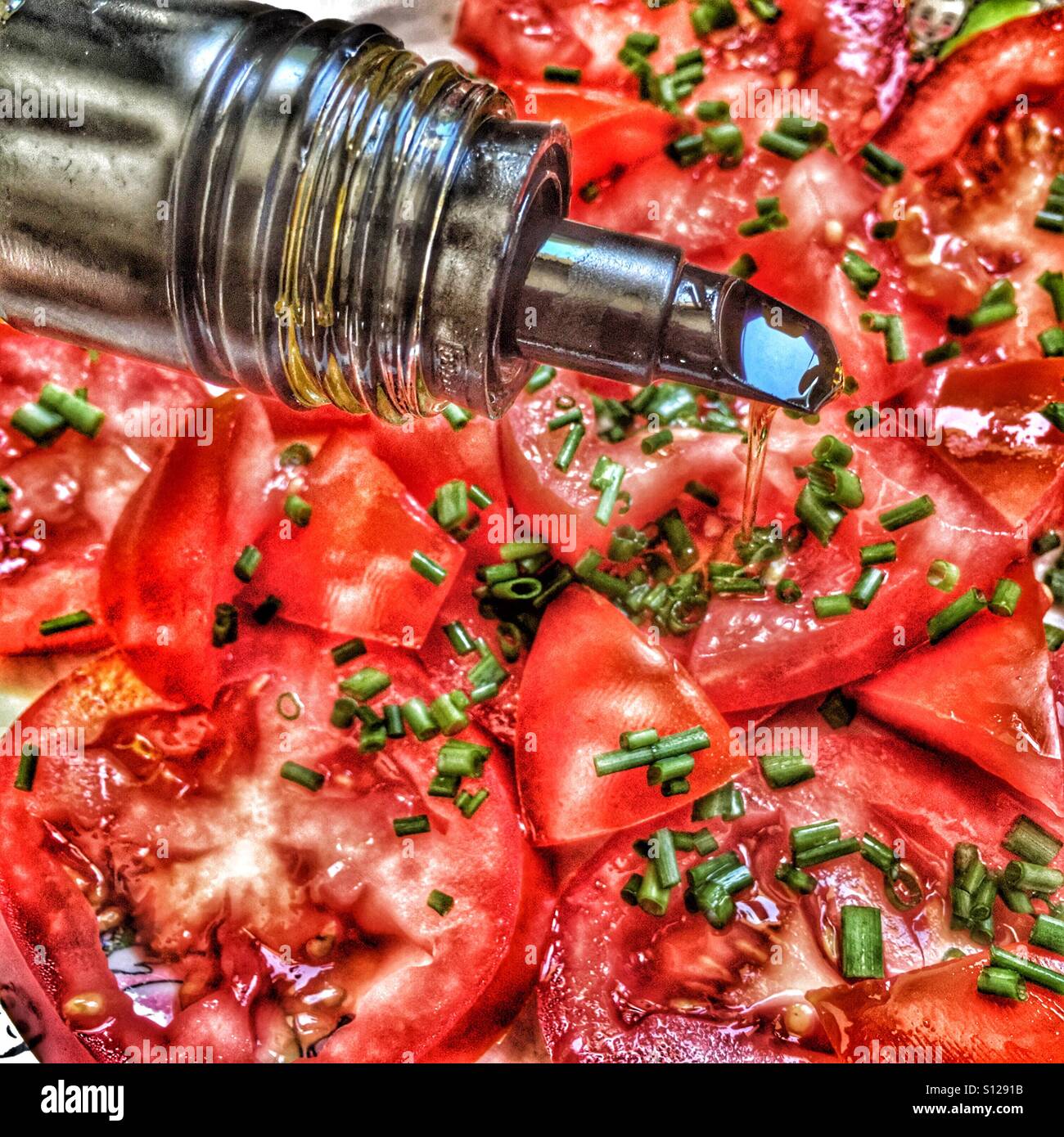 Drizzling olive oil onto tomato salad - Smartphone Captured Stock Image