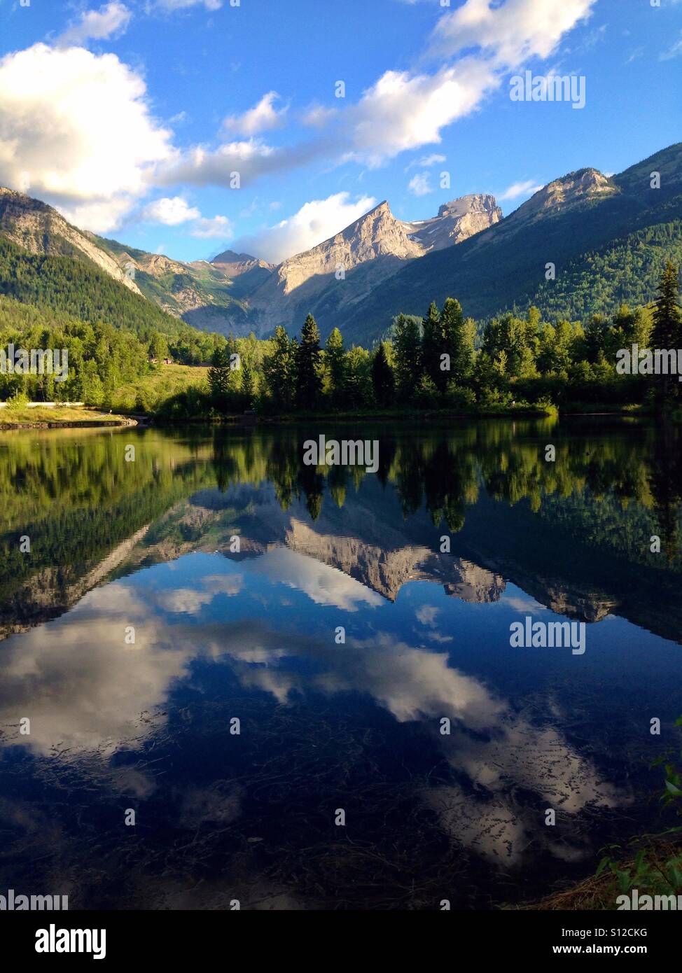Mountains and clouds reflected in a lake Stock Photo - Alamy
