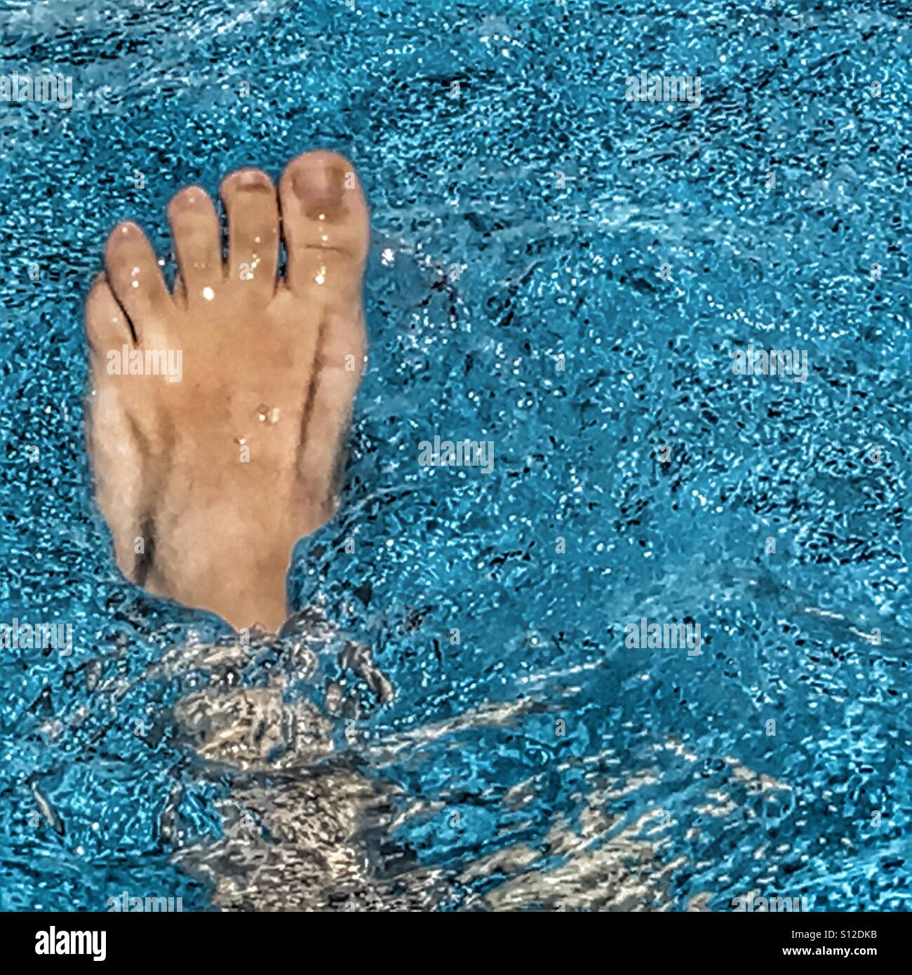 POV foot in swimming pool, cooling down Stock Photo