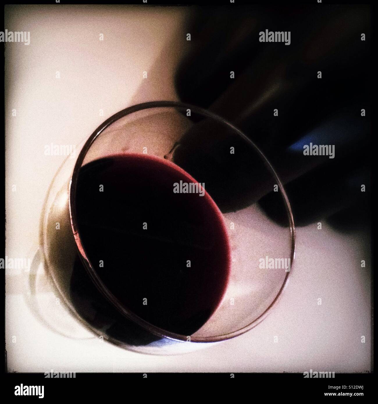Red Syrah wine in a glass, with bottles. - Smartphone Captured Stock Image