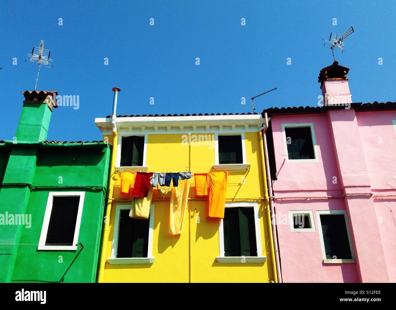 Hung out to dry: washing on the line outside a row of old, brightly painted houses in the popular tourist day trip destination of Burrano, the Benetian island famous for lace-making. Stock Photo