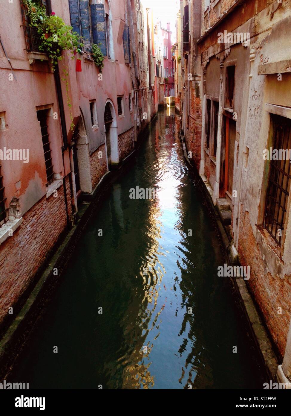 Historic houses flank both sides of a narrow canal in Venice. Stock Photo