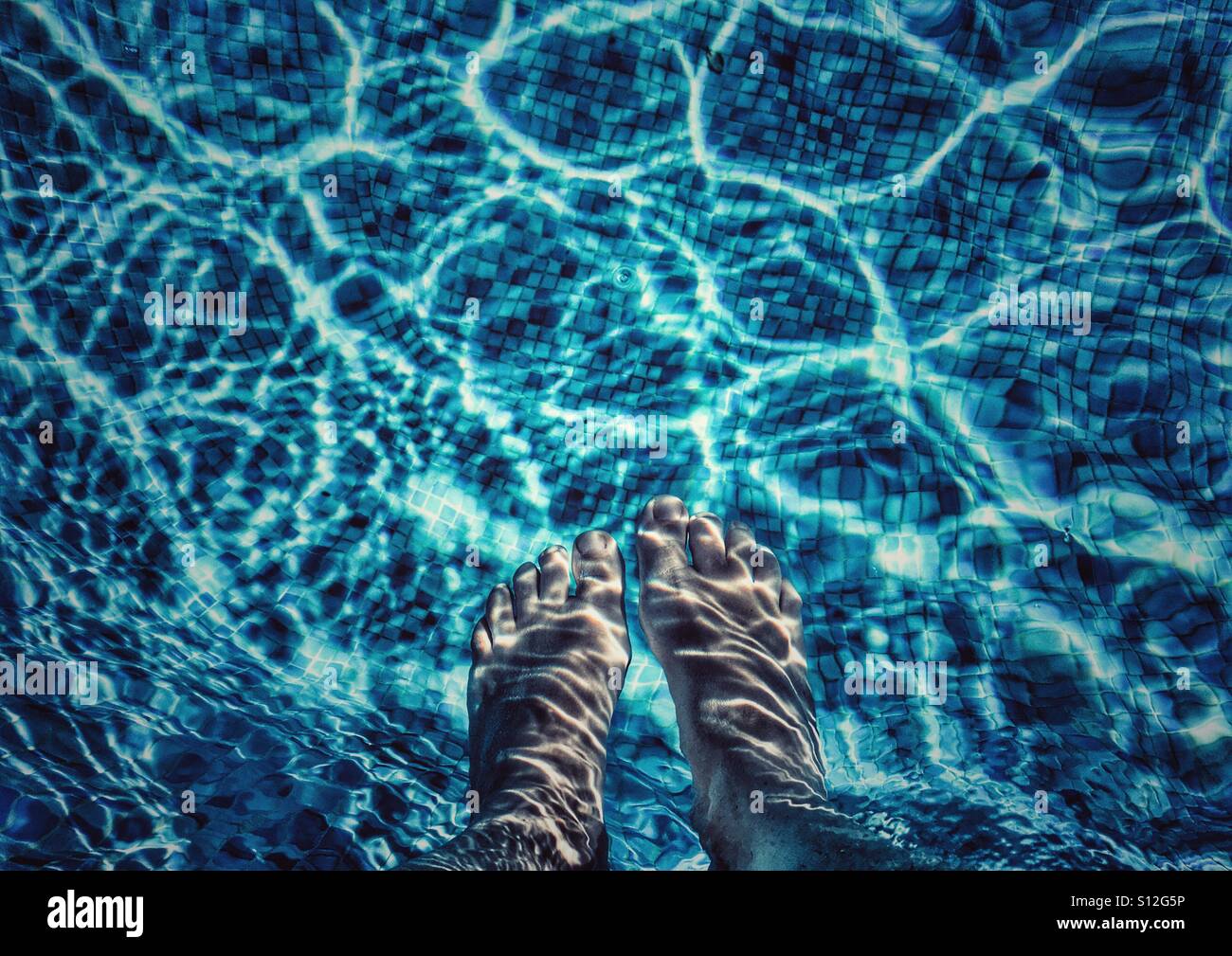 Summer fun. POV.  Feet in swimming pool. - Smartphone Captured Stock Image