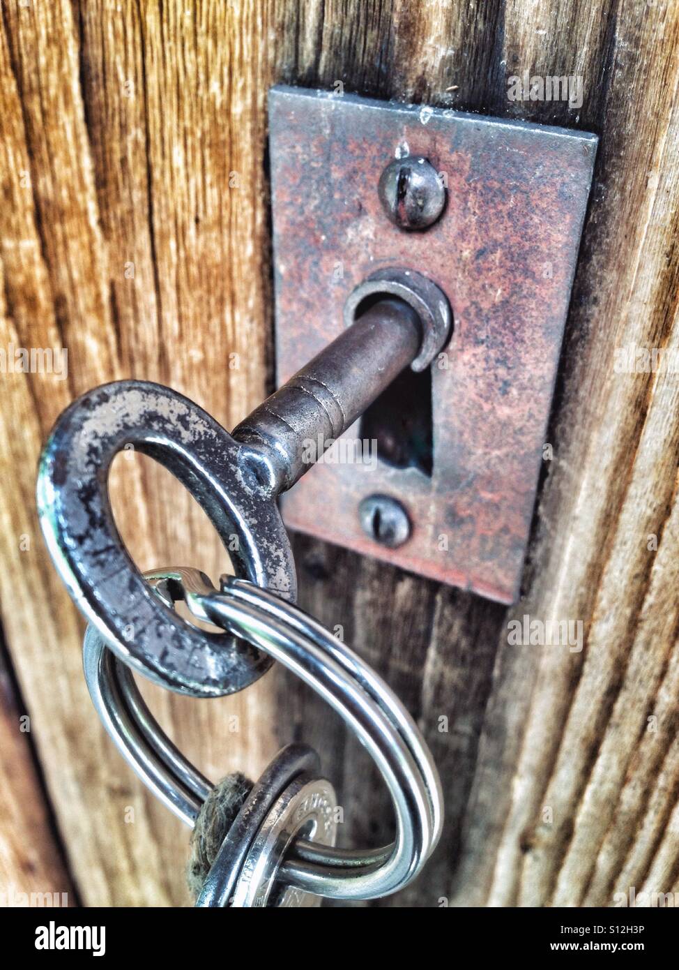 Keys in a metal keyhole on a wooden door - Smartphone Captured Stock Image