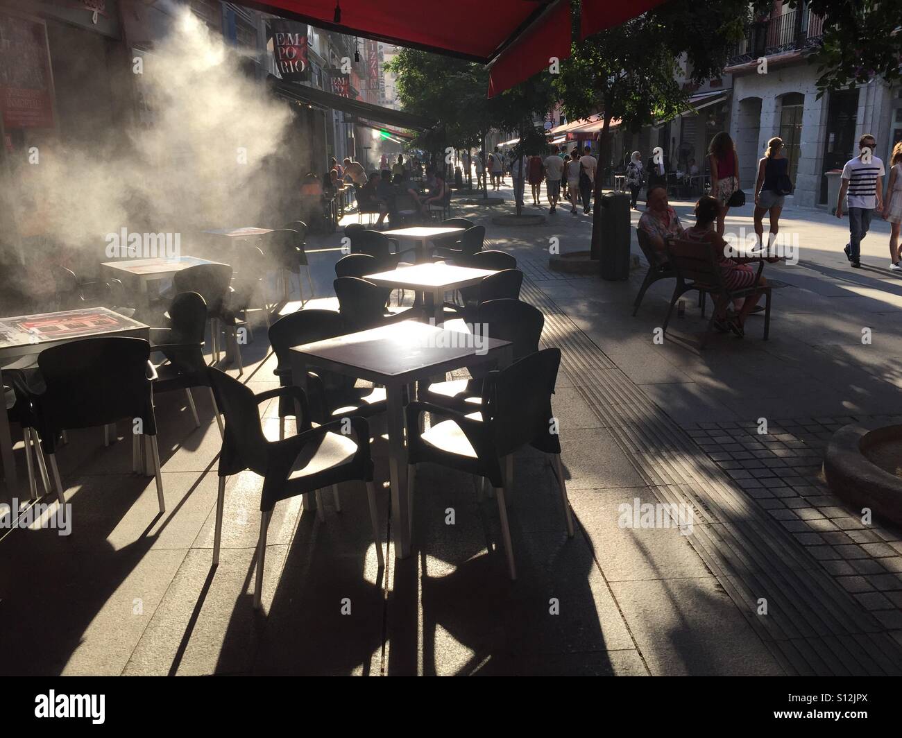 A cooling mist from outdoor air conditioning at a cafe's terrace in Madrid, Spain as temperatures reach 38 degrees - Smartphone Captured Stock Image