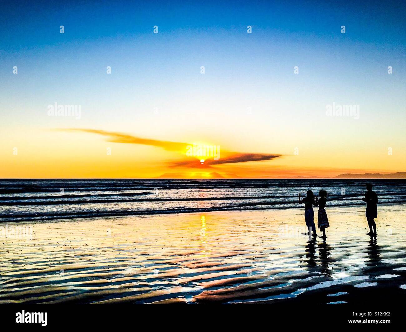 Beautiful sunset over sea, reflection on beach at Stand with children. Stock Photo