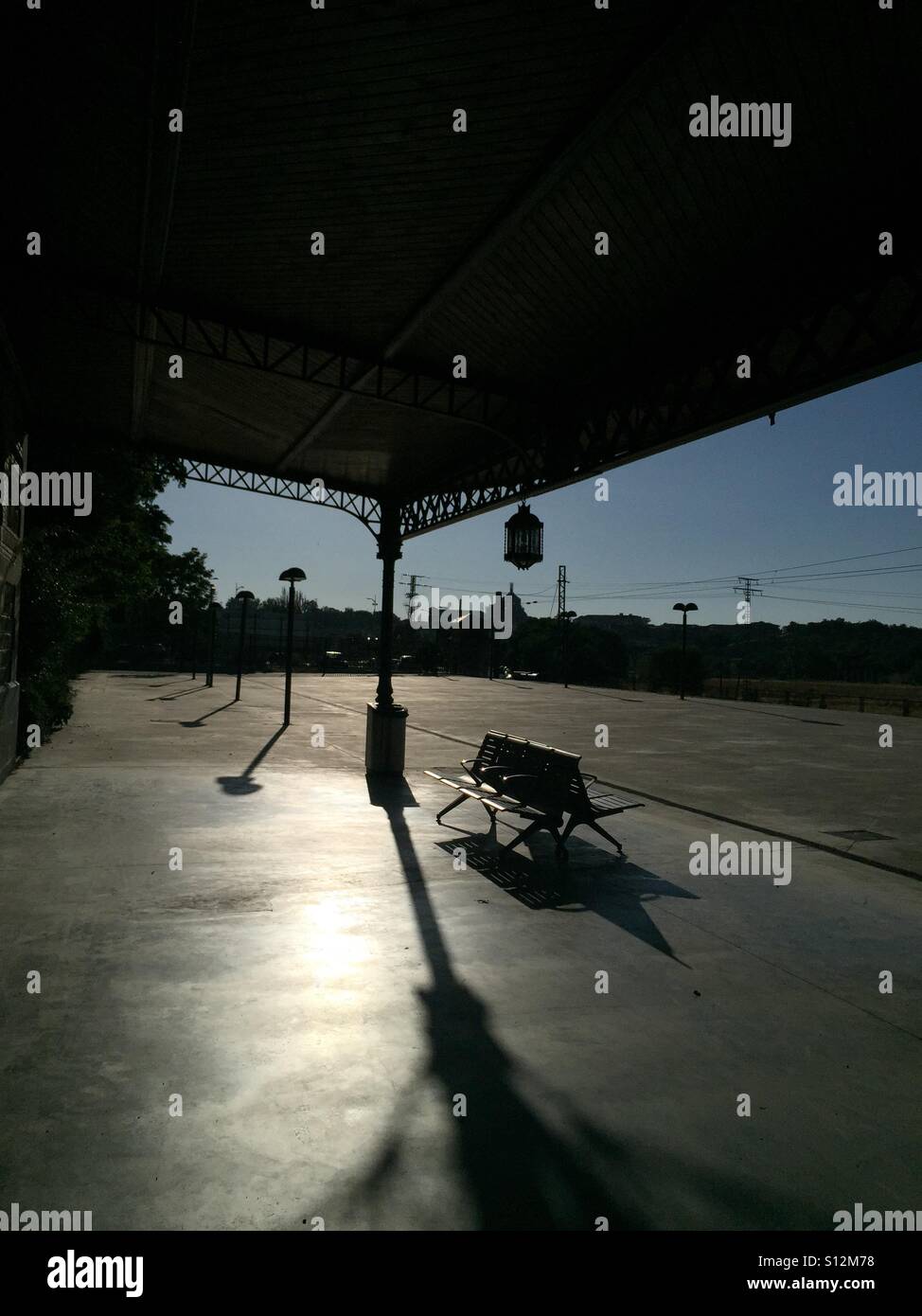 Empty train station and bench in early evening sunlight with long shadows in Toledo, Spain - Smartphone Captured Stock Image