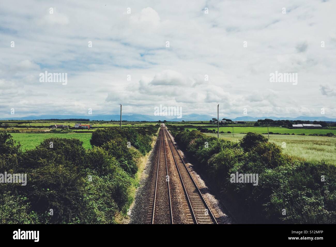 Railway through Anglesey, North Wales, looking toward Snowdonia Stock Photo