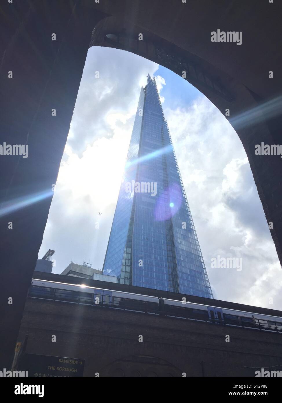 Old London and new. A plane passes the shard, framed by a Victorian brick arch - Smartphone Captured Stock Image