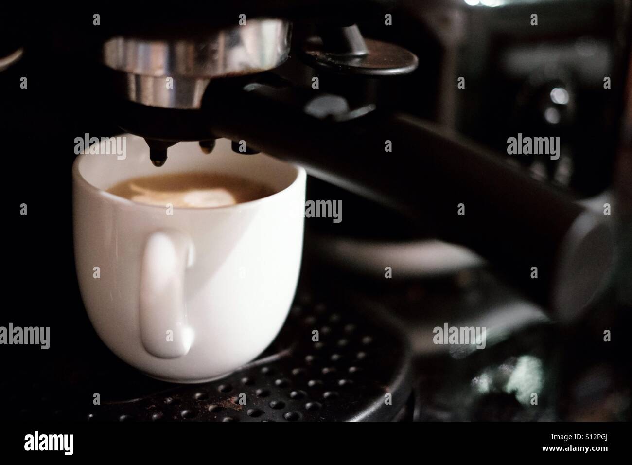 White cup filling with coffee from a home coffee maker. Espresso maker