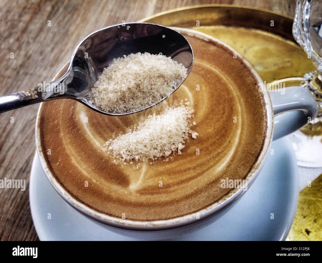 Putting sugar in a cup of cappuccino - Smartphone Captured Stock Image