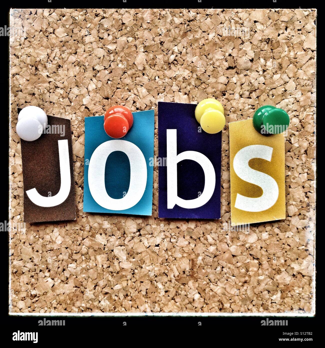 The word JOBS in cut out magazine letters pinned to a cork notice board Stock Photo