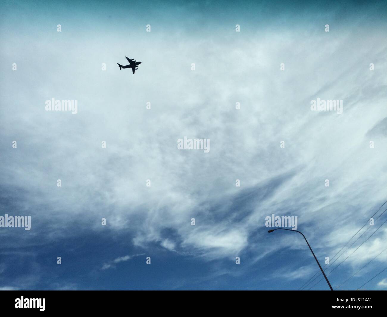 Plane flying across a cloudy sky. Stock Photo