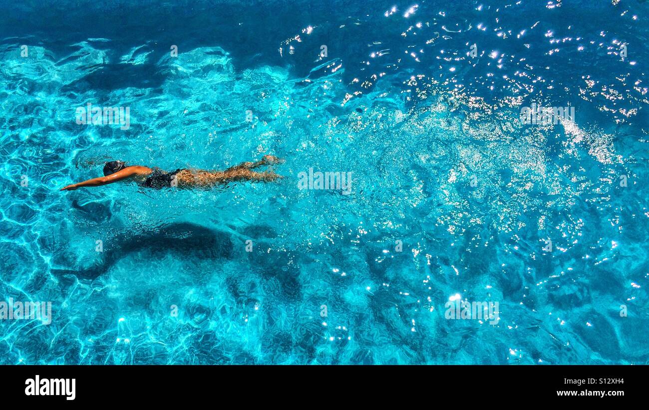 High angle view of a fit woman swimming outdoors in swimming pool on a sunny day - Smartphone Captured Stock Image