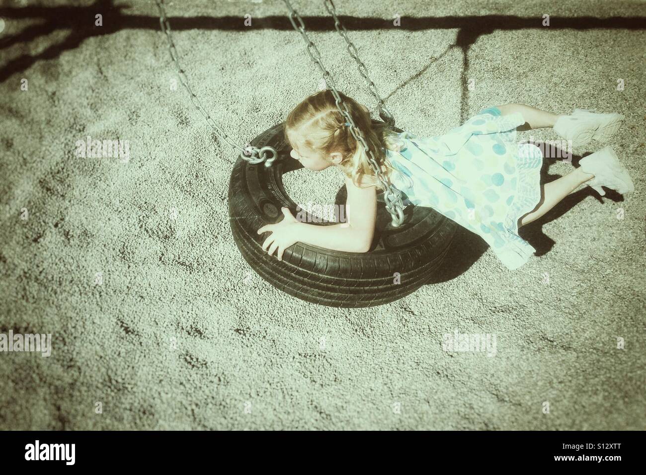 A girl glides on a tire swing. - Smartphone Captured Stock Image