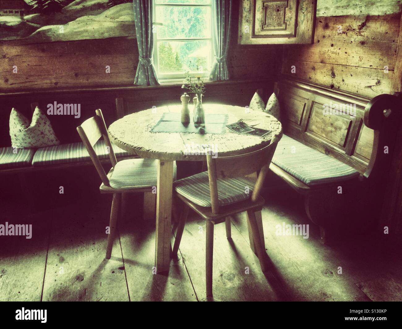 a round corner table with two chairs and a bench in the