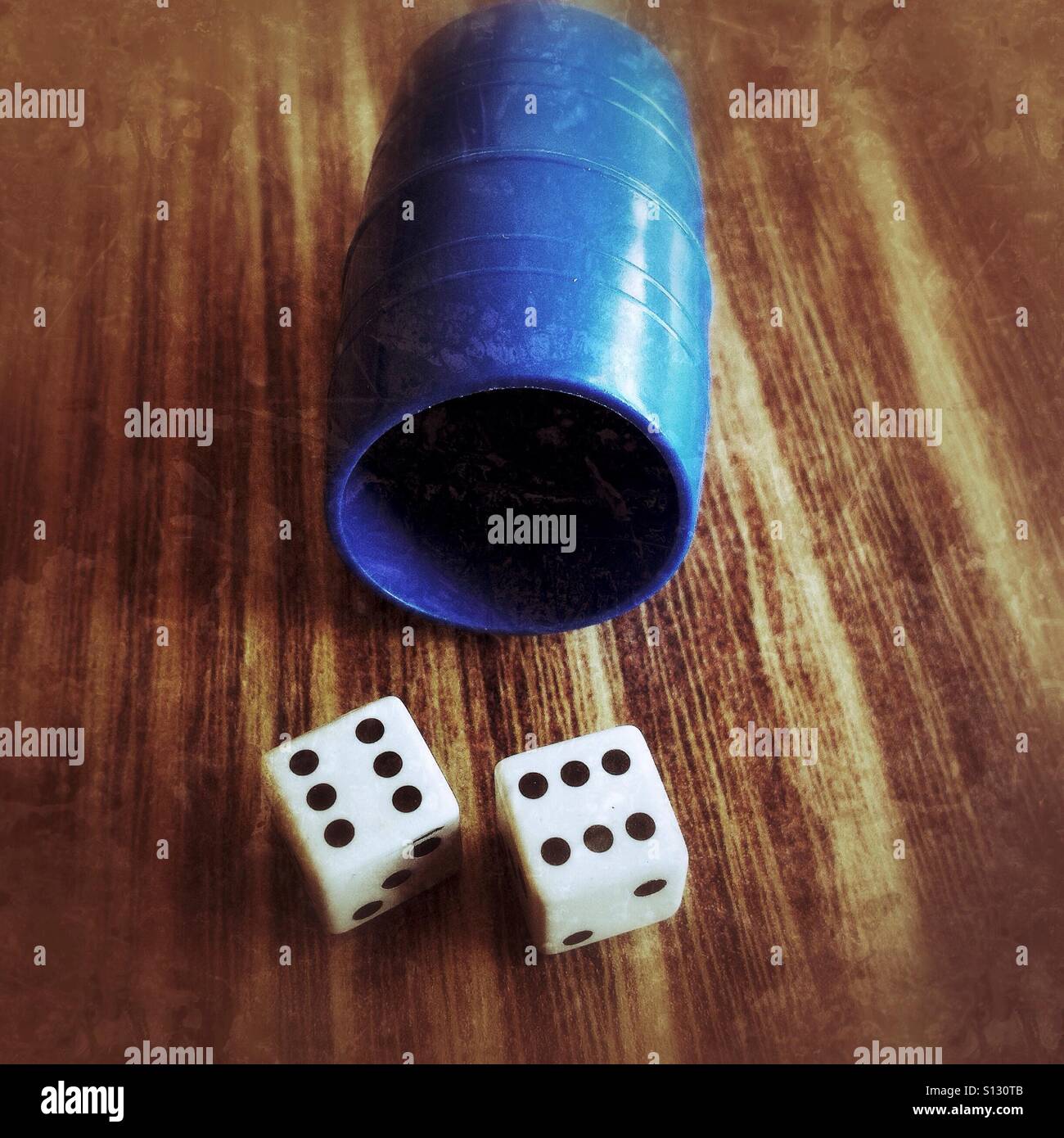 Two dices and a blue cup on a wooden table - Smartphone Captured Stock Image