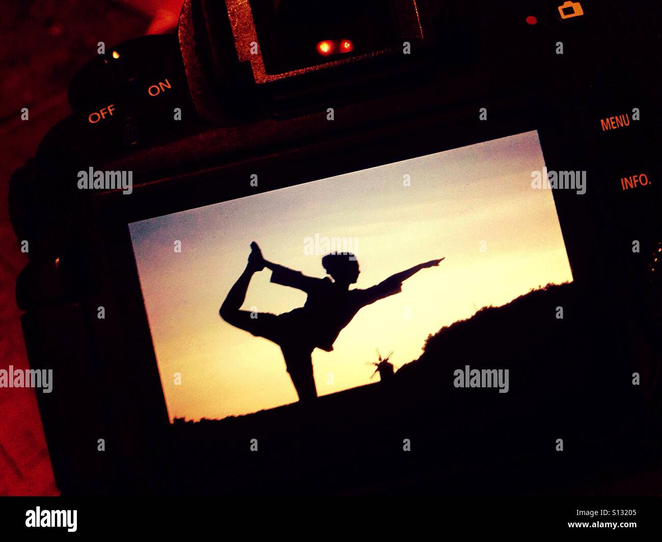 Silhouette of woman making Natarajasana yoga pose displayed on the camera screen - Smartphone Captured Stock Image