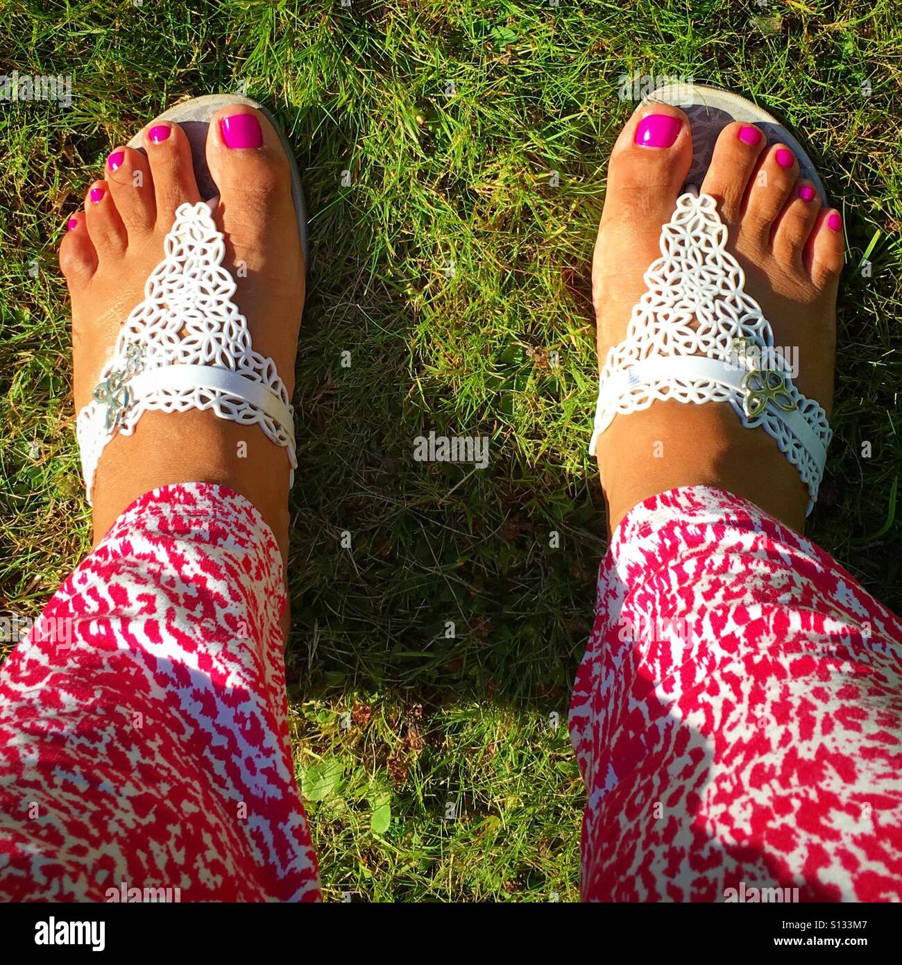 Hot pink pedicure in white sandals Stock Photo
