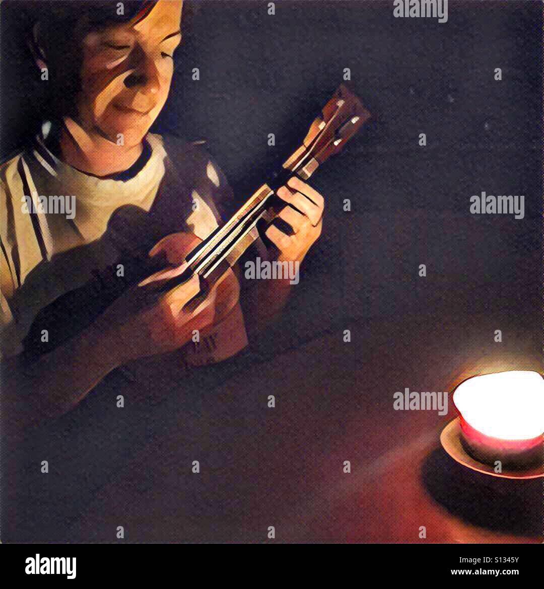Woman playing ukulele by candle light - Smartphone Captured Stock Image