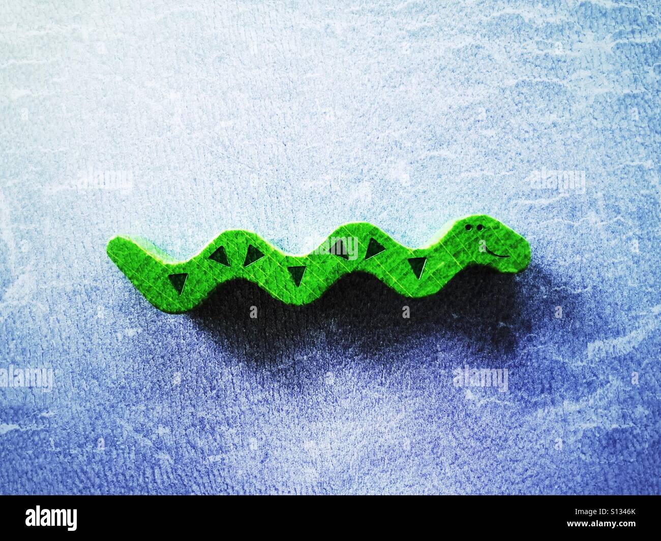 One wooden toy snake on a blue background. 1 of 3 in a series. - Smartphone Captured Stock Image