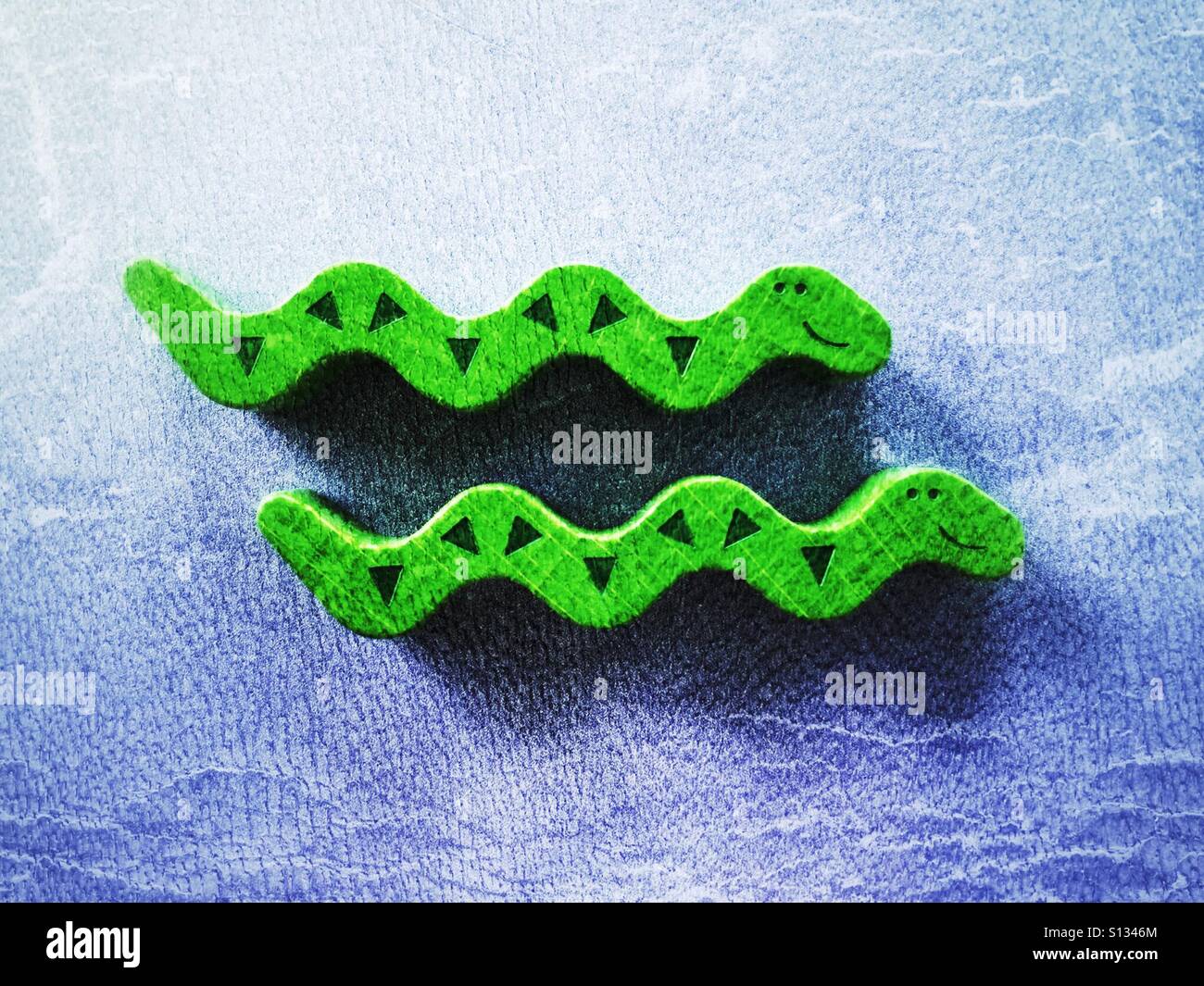 Two wooden toy snakes on a blue background. 2 of 3 in a series. - Smartphone Captured Stock Image