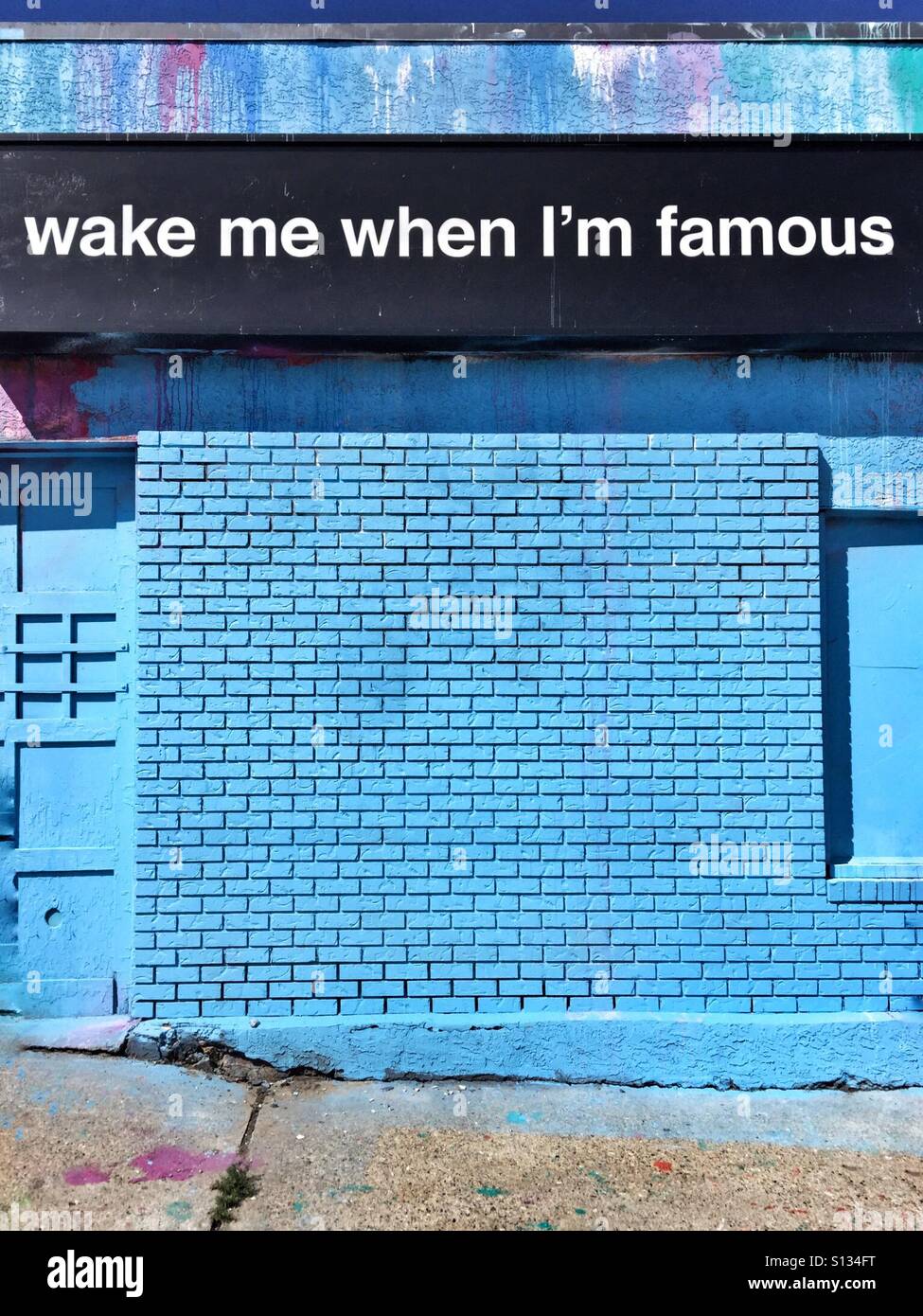 A sign on the front of a blue building reads 'wake me when I'm famous'. - Smartphone Captured Stock Image A sign on the front of a blue building reads 'wake me when I'm famous'. - Smartphone Captured Stock Image