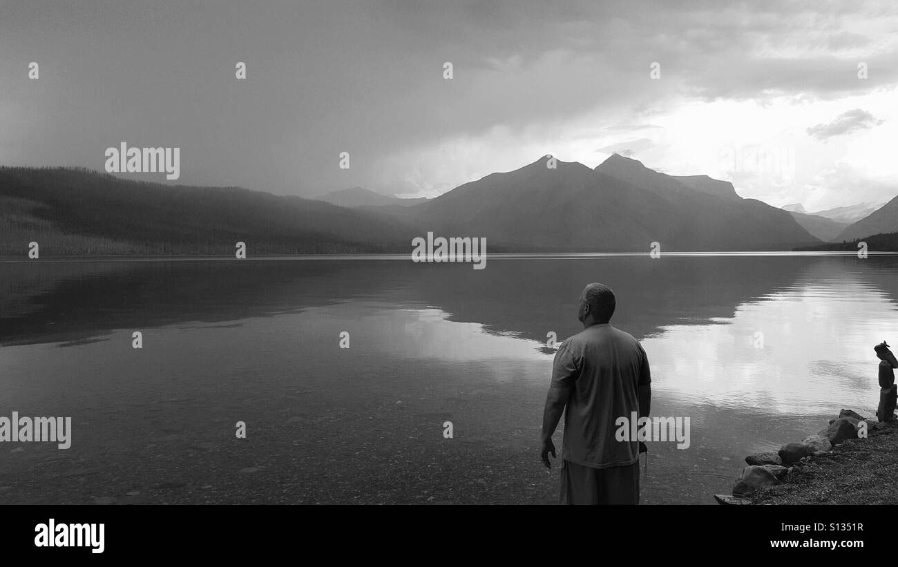 Man looks out at an approaching storm at McDonald Lake in Glacier National Park. Stock Photo