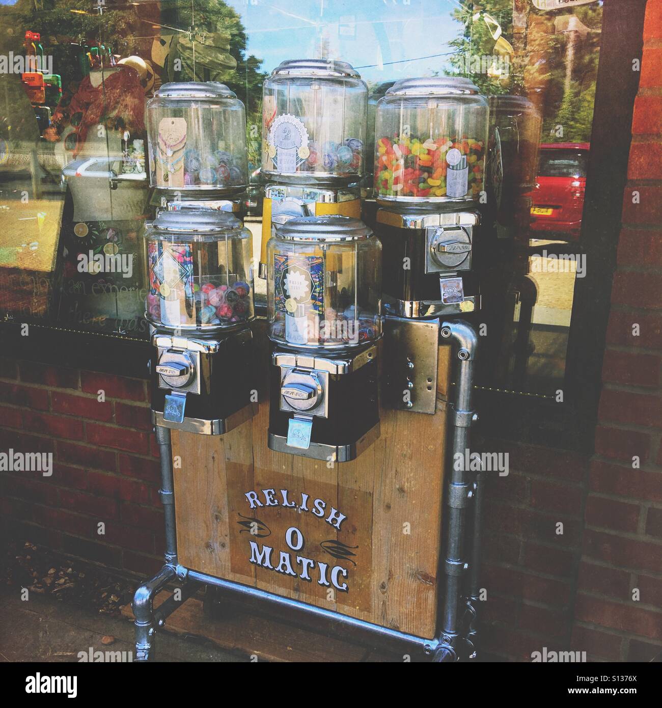 Vintage candy vending machine filled with colourful sweets, styled with industrial metal pipes and wood, evoking nostalgia and retro street culture. - Smartphone Captured Stock Image